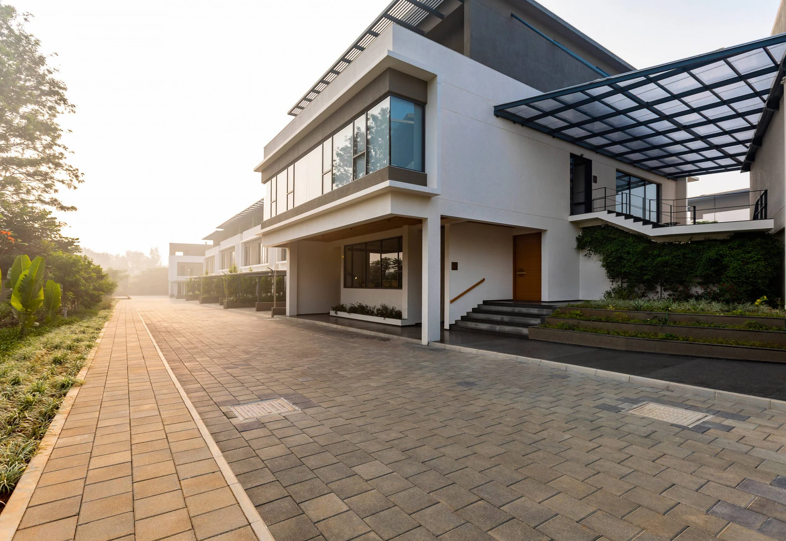 Wide paved internal street lined with independent villas in warm evening light at Alanoville in Bengaluru