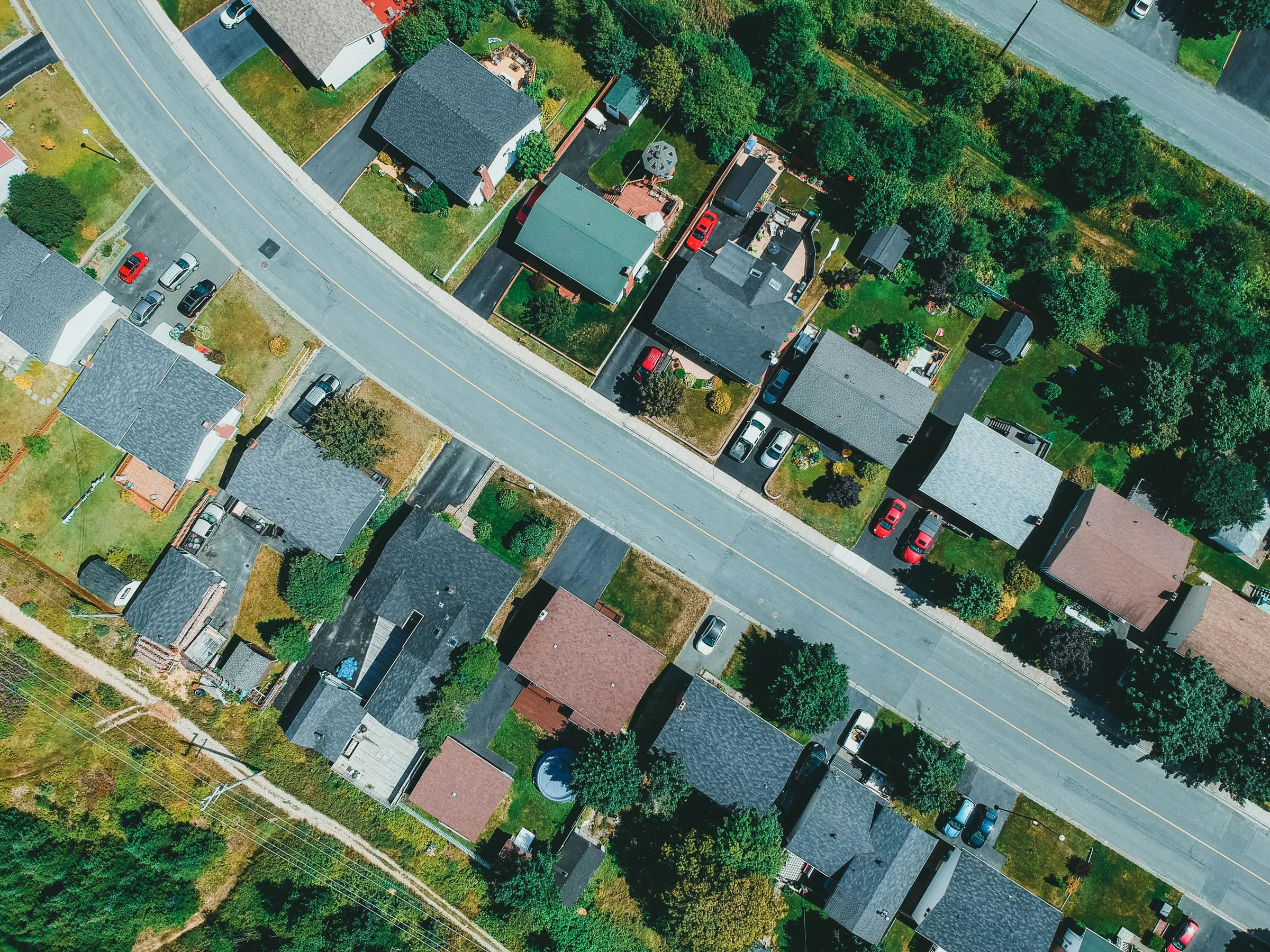 Aerial view of a neighborhood with detached homes, lawns and connected streets